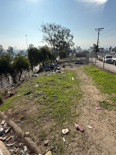 A relatively small homeless encampment next to a freeway 