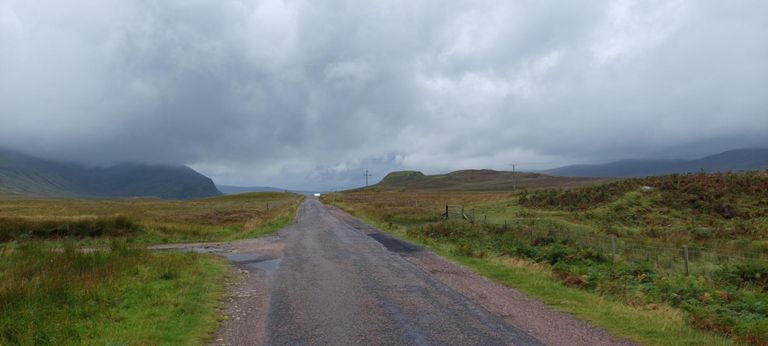 Hills l>r: slope down from 2536ft/773m Beinn  Spinionnaidh or 1706ft/520m Cioch Mor, then cloud-covered peak of 1148ft/350m Cioch Bheag. On the right of the road: 177ft/54m Preas Mor. Left of road hill photo in sunnier weather: https://www.geograph.org.uk/photo/6839604