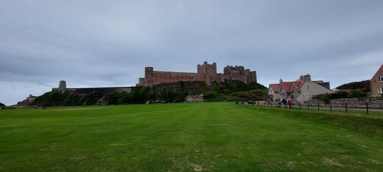 Bamburgh Castle and windmill to left of the castle. 12th century ruin with extensive rebuilding, 1894-1904. Already past 14.00 so a need to continue after food. Lots of tourists or locals pubbing for lunch.  After lengthy queuing, we got foods snd drink at the Wyndenwell cafe and ate outside with views of the castle and the green, having taken it in turns to queue or watch the bikes. There was one other local cyclist. And a visitor from India sitting quietly, reading a book, and with a lovely smile I told her. https://historicengland.org.uk/listing/the-list/list-entry/1280155?section=official-list-entry \u0026 https://www.bamburghcastle.com \u0026 https://historicengland.org.uk/listing/the-list/list-entry/1370967