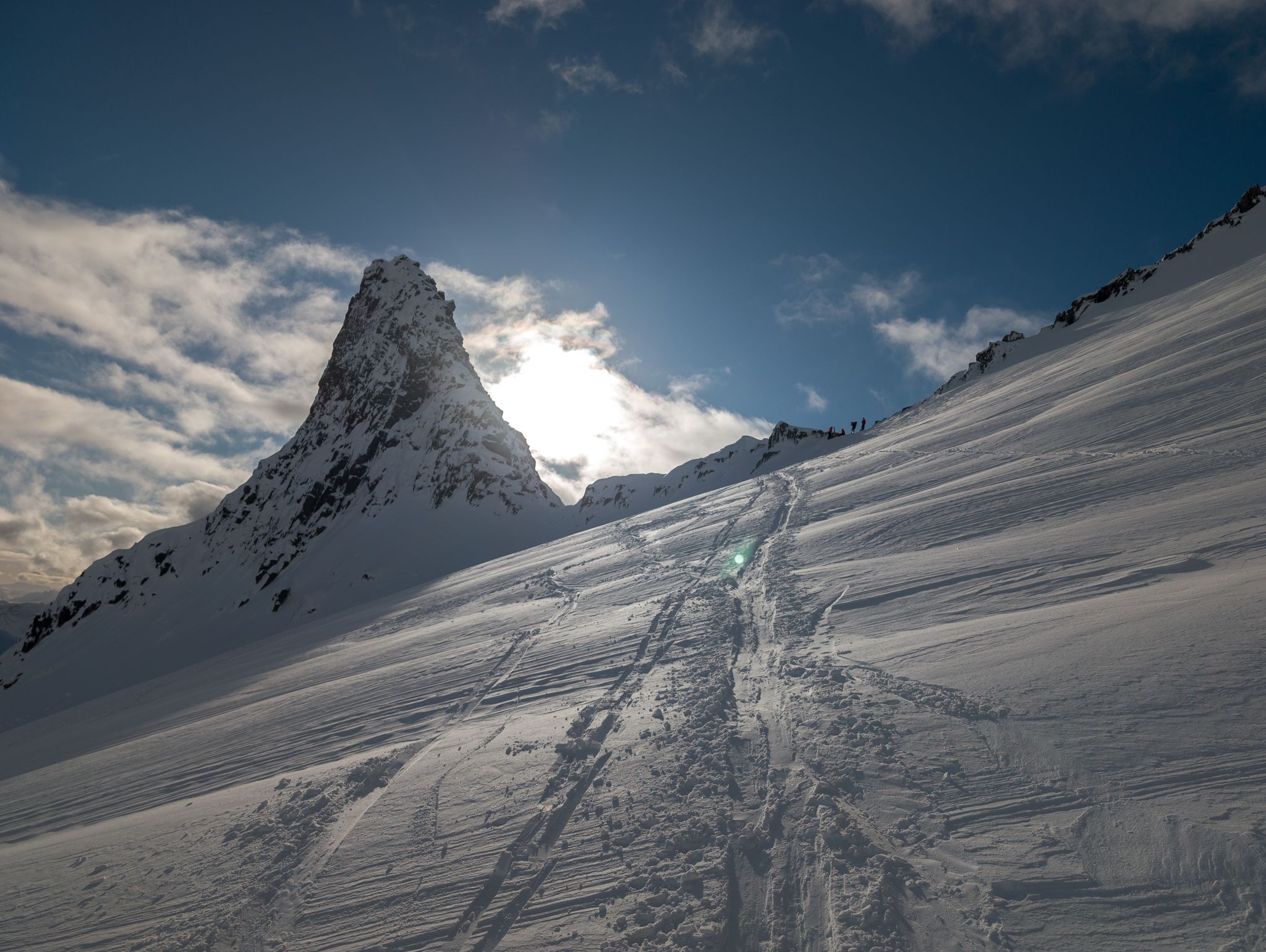 Den markerte Fingeren med skispor og skiløpere i den snødekte fjellsiden