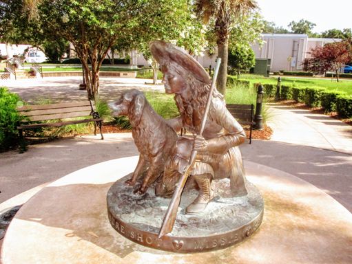 A bronze statue of Annie Oakley with Dave behind the Leesburg library.