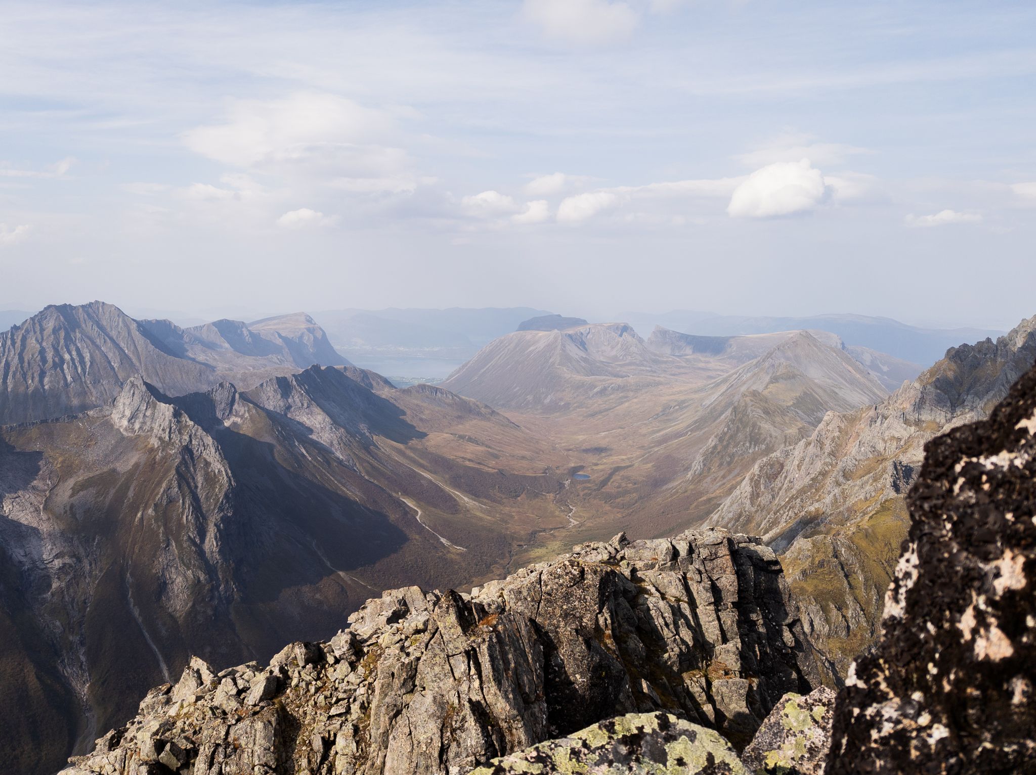 Daler, fjellplatåer og et lite vann sett fra Storegjøltinden