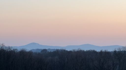 Ein Blick zum Zittauer Gebirge mit der Lausche, die als linke Erhebung im Licht der Dämmerug in den Himmel ragt.