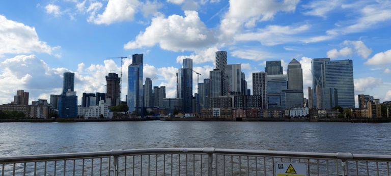 @13.44: Viewed from the northerly tip of Greenwich Peninsula: London Docklands, including right to left: Barclays Bank (opened 2005) in front of taller HSBC (2002), then Canary Wharf (1991), then Citi (bank, 2002),  various then the taller and round Herzog and de Meuron One Park Drive (2022). My favourite: shiny blue Dollar Bay (2017). Tall round one is Arena aka Baltimore Tower (2016).  https://en.wikipedia.org/wiki/List_of_tallest_buildings_and_structures_in_London  &  https://www.herzogdemeuron.com/projects/404-one-park-drive/ &  https://www.youtube.com/watch?v=gXvmQ5ZoIcc
