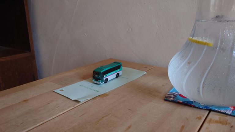 テーブルの端に置いてあったバスのミニカー、ただのオブジェかと思ったらこういう使い方をするのね...　あ、お冷はレモン水でした。