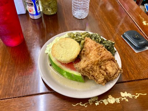 A light breakfast of fried chicken, watermelon, smoked ribs, potato salad, green beans, collard greens, corn bread, sweet tea, and peach cobbler with vanilla ice cream.