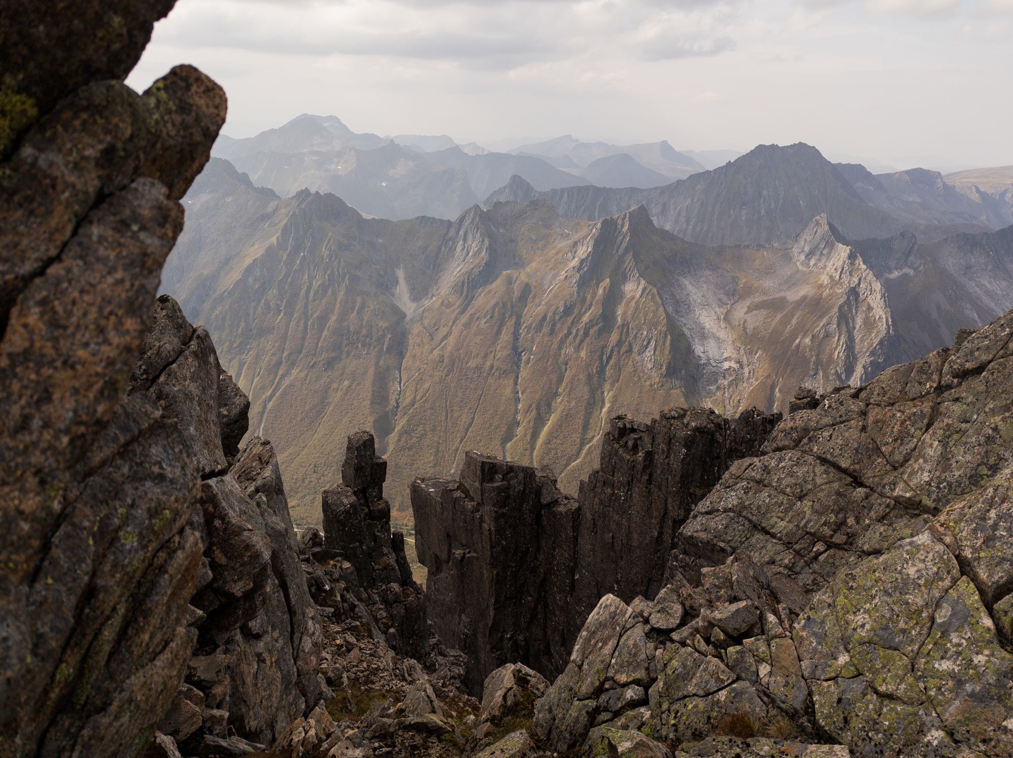 Bratte bergformasjoner i forgrunnen og fjellrygger i bakgrunnen