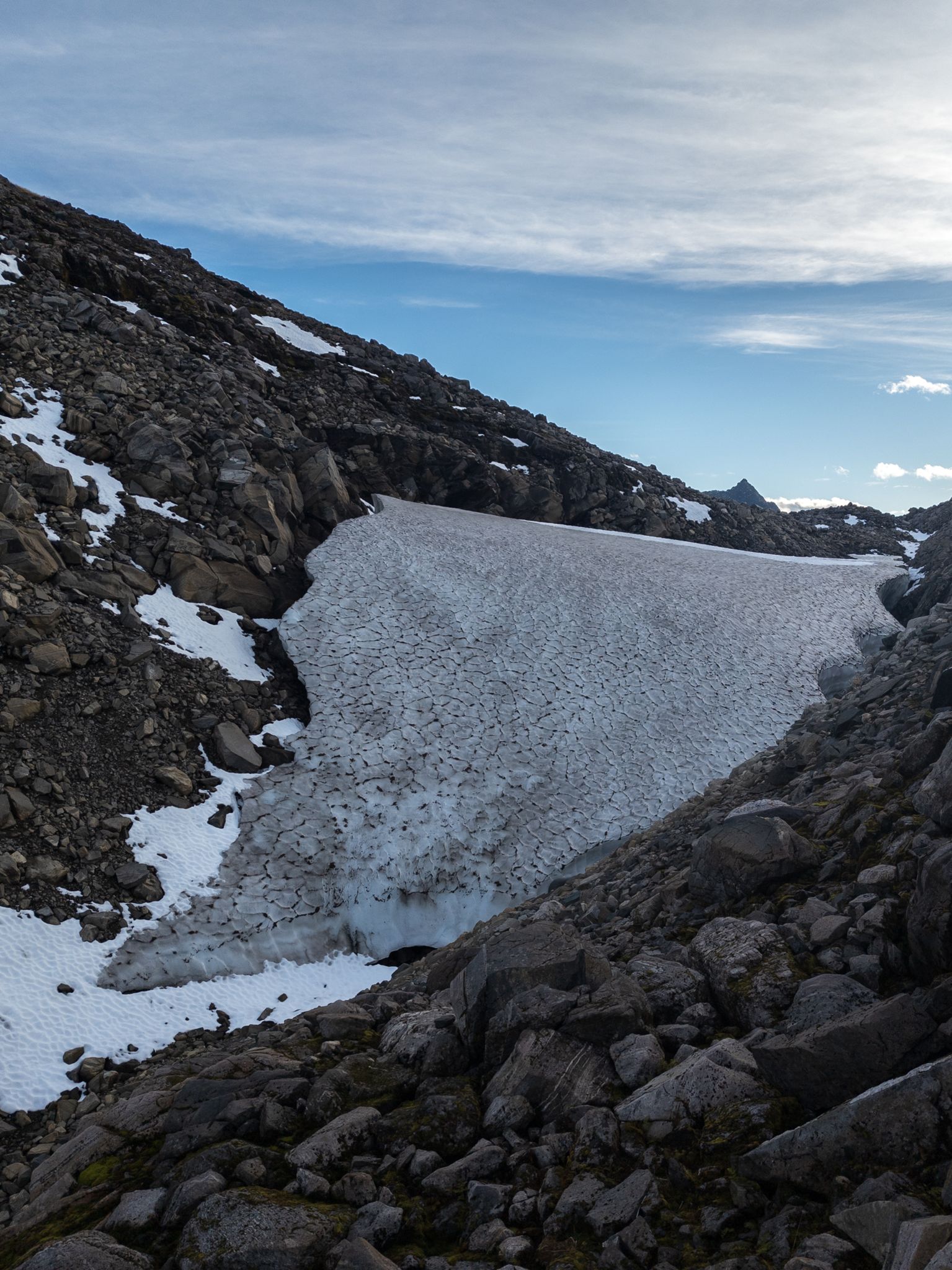 Et stort, sprukket snøfelt mellom stein og ur i høyden