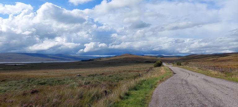 Looking back at a straight line of rain cloud. The nearest brown hill is 646ft/197m Cnoc a Laoigh.  Further back is 932ft/284m Druim na Claise Carnaich. River Fiag is between them.