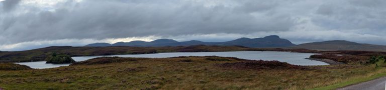 Loch Crocach, a name shared with 4 others.   Looking at the seven dark peaks on the horizon, I prayed our route avoided them - somehow.  L>R (possibly): 538ft/164m Creag an Breac, 492ft/150m Cnoc Airigh na Meinne, 1017ft/310m Meall Leathad na Craoibhe, Beinn Bhreac, 1102ft/336m Meall nan Clach Ruadha, then with antenna 991ft/302m Ben Tongue and to its right, the ominous 1007ft/307m peak named Cnoc an Freiceadain, then the lower green hill is 614ft/187m Ben Blandy. https://en.wikipedia.org/wiki/Cnoc_an_Fhreiceadain